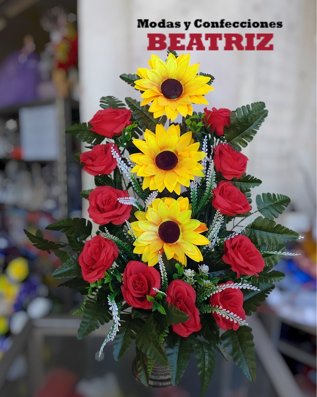 Arreglo floral de rosas rojas y girasoles amarillos con follaje verde en base alta de barro - Modas y Confecciones Beatriz