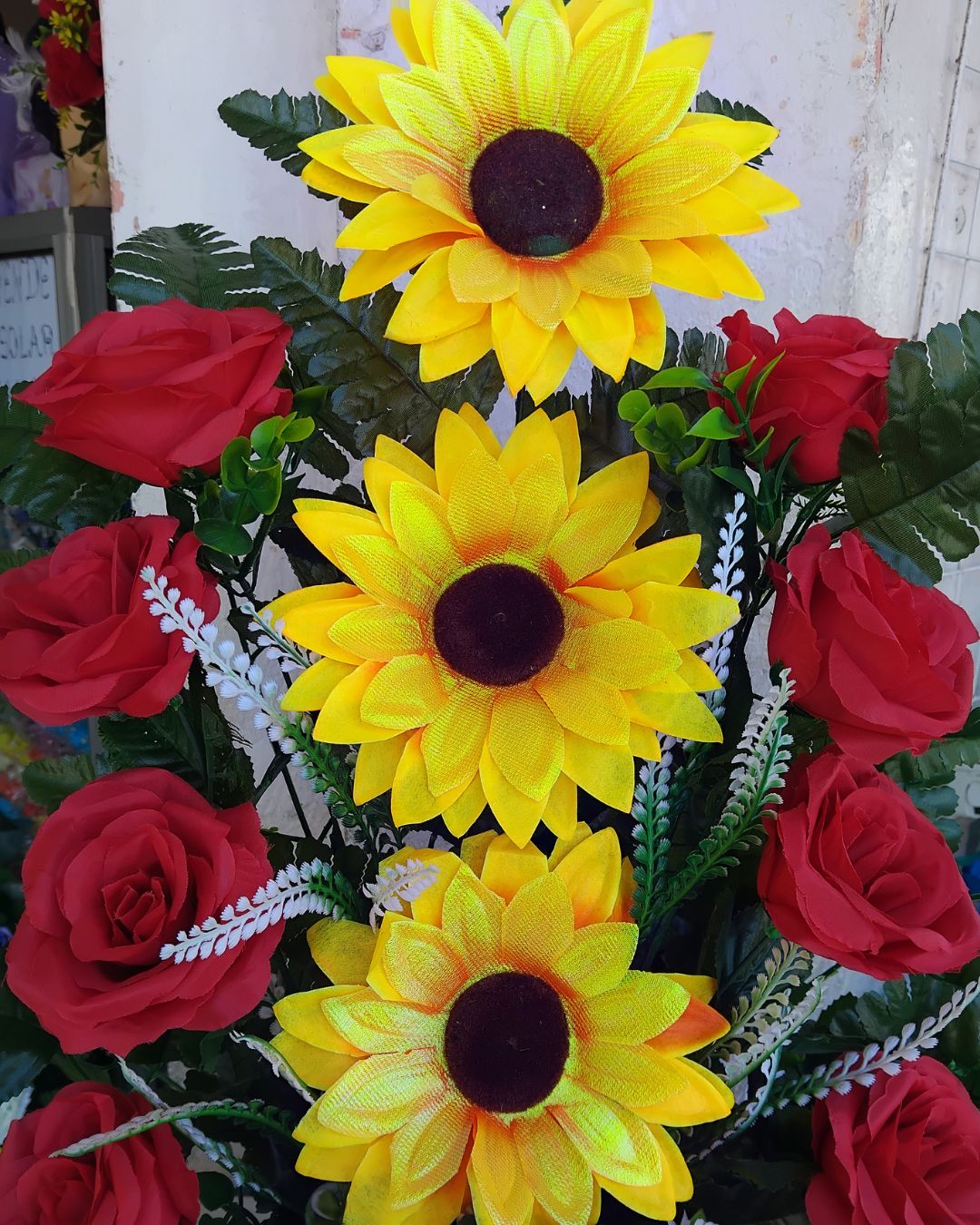 Detalle de girasoles amarillos y rosas rojas del arreglo floral con follaje verde y blanco - Modas y Confecciones Beatriz
